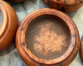 May include: A set of four wooden bowls with a dark brown finish. The bowls are round and have a smooth, polished surface. The bowls are perfect for serving snacks, dips, or other small dishes.