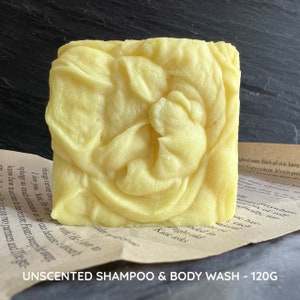 May include: A bar of unscented shampoo and body wash in a yellow color. The bar is 120 grams and is sitting on a piece of paper with text.