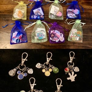 May include: An assortment of small gift bags in various colors, filled with trinkets and charms. Below, several keychains with Mickey Mouse-themed charms and heart-shaped tags that say "Thank You" are displayed on a black surface.