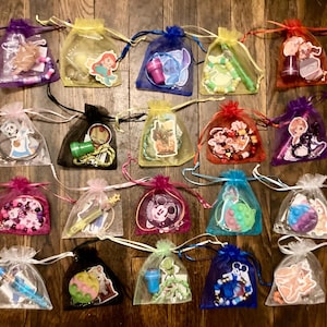 May include: A collection of small, colorful organza bags tied with ribbons. Each bag contains various charms, beads, and small toys. The bags are in a variety of colors, including purple, yellow, red, and blue. The contents include cartoon characters.