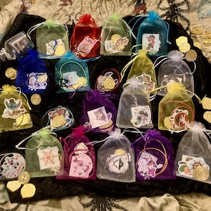 May include: A collection of small, colorful, sheer bags filled with gold coins and small trinkets. The bags are arranged on a black velvet surface.