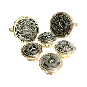 May include: A set of gold-toned cufflinks and shirt studs. Each piece features a circular design with the words "THE STATE OF TEXAS" encircling a star emblem. The set includes two pairs of cufflinks and four shirt studs.