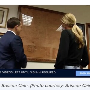 May include: A man and a woman are looking at a framed map. The map is brown and has a white seal in the lower right corner. The man is wearing a dark suit and the woman is wearing a black shirt and jeans. The text on the image reads "4 VIDEOS LEFT UNTIL SIGN-IN REQUIRED" and "SIGN IN". The text below the image reads "Rep. Briscoe Cain. (Photo courtesy: Briscoe Cain)".