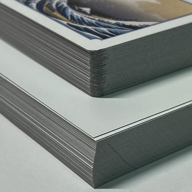 May include: A stack of white cards with a printed image of a blue wave on the top card.