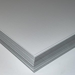 May include: A stack of white cardstock paper with a smooth, slightly textured surface.