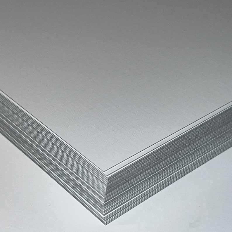 May include: A stack of white cardstock paper with a smooth, slightly textured surface.