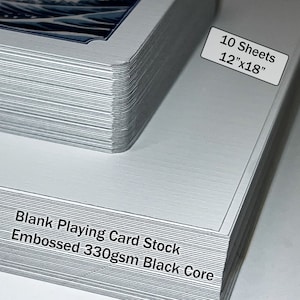 May include: A stack of 10 blank playing card stock sheets, each measuring 12" x 18". The sheets are embossed and have a black core. The text "Blank Playing Card Stock Embossed 330gsm Black Core" is printed on the side of the stack.