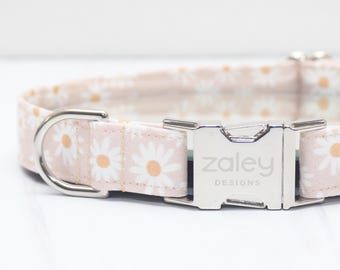 May include: A pink and white dog collar with a daisy print and a silver buckle that says "zaley designs".