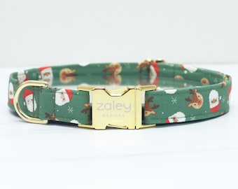 Puede incluir: Un collar verde para perros con un estampado navideño festivo con Papá Noel, renos y copos de nieve. El collar tiene una hebilla y una anilla en D doradas. El texto "Zaley Designs" está impreso en la hebilla.