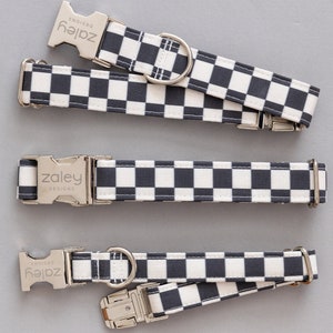 May include: Three dog collars with a black and white checkered pattern. The collars have silver metal buckles and D-rings. The brand name "zaley designs" is printed on the buckles.