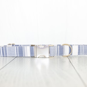 May include: A blue and white plaid dog collar with a silver buckle and gold D-rings.