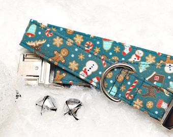 May include: A teal blue dog collar with a festive Christmas pattern featuring gingerbread men, candy canes, snowflakes, and snowmen. The collar has a silver buckle and two silver bells.
