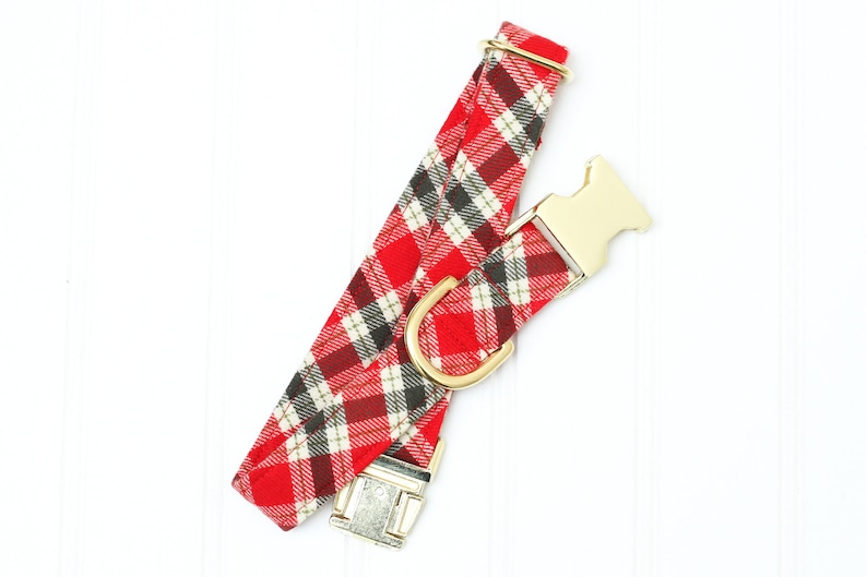 Op de afbeelding: Hondenhalsband van rood en zwart geruit stof met gouden gespen.