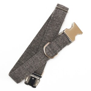 Puede incluir: Un collar de perro de color marr&oacute;n y negro con estampado de espiga y hebilla de metal plateado.