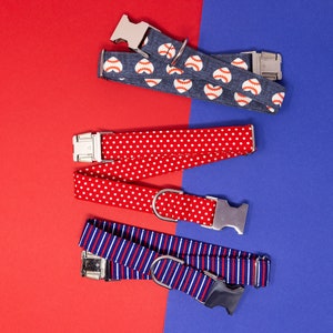 Puede incluir: Cuatro collares para perros con diferentes patrones. Los collares est&aacute;n sobre un fondo rojo y azul. Los collares son azules con pelotas de b&eacute;isbol blancas, rojos con lunares blancos, azules y rojos a rayas, y rojos con lunares blancos.