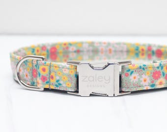May include: A green, yellow, and pink floral dog collar with a silver buckle that says "zaley designs".