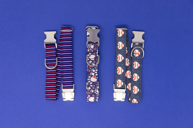 Puede incluir: Cuatro collares de perro diferentes con varios patrones. Los collares son azules, rojos, blancos y grises con diferentes patrones que incluyen rayas, huellas de patas y pelotas de b&eacute;isbol.