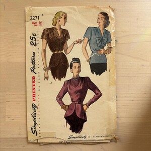 May include: A vintage Simplicity pattern, number 2271, showing illustrations of three blouses. The pattern includes bust 91 cm and hip 99 cm measurements. The cover is aged and priced at 25c.