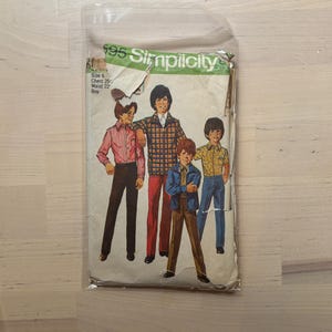 Puede incluir: Patrón de costura Simplicity vintage para ropa de niño. El paquete de patrones muestra ilustraciones de niños con varios atuendos. El texto en el paquete incluye "Simplicity" e información sobre tallas.