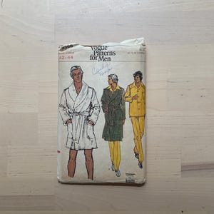 May include: Vintage Vogue Patterns for Men sewing pattern. The package features illustrations of men's clothing, including a robe, coat, and suit. The pattern size is Large, 42-44. The text "Candy Tange" is handwritten on the package.