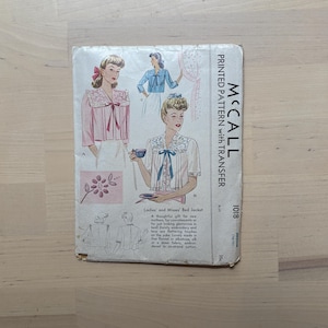 May include: Vintage McCall's sewing pattern for a Ladies' and Misses' bed jacket. The pattern features illustrations of the jacket in various styles, with details on embroidery and lace. The cover is aged, with the text "PRINTED PATTERN with TRANSFER".