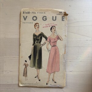 May include: A vintage Vogue pattern envelope, tan in colour, with illustrations of two dresses. The envelope includes the text "VOGUE PATTERN" and size details. The illustrations show a green, long-sleeved dress and a pink dress with short sleeves.