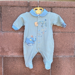 Puede incluir: Un pelele de beb&eacute; a rayas azules y blancas con una aplicaci&oacute;n de jirafa y elefante. El pelele tiene un cuello blanco y un cierre de botones.