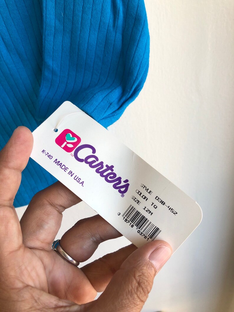 May include: A white tag with the Carter's logo and text that reads "STYLE 038-452 COLOR TO SIZE 12M K-740 MADE IN U.S.A."  A barcode is below the text.