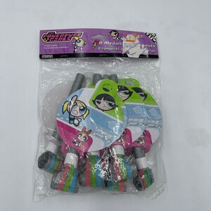 May include: A pack of 8 Powerpuff Girls party blowouts. The blowouts are colourful and feature the Powerpuff Girls characters. The pack is pink and purple with the text "The Powerpuff Girls" and "8 Medallion Blowouts".