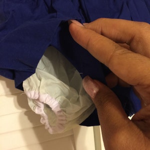 May include: Blue and white baby diaper cover with elastic waistband. The cover has a white elastic trim around the leg openings.