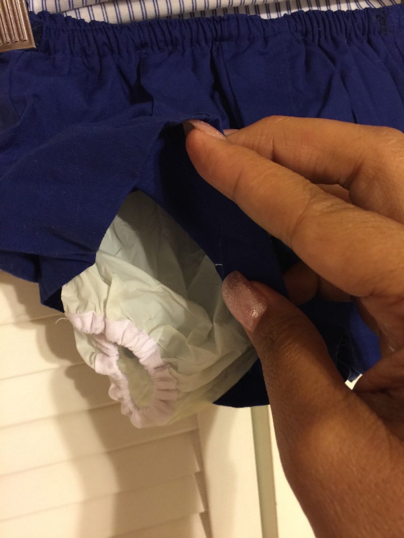 May include: Blue and white baby diaper cover with elastic waistband. The cover has a white elastic trim around the leg openings.