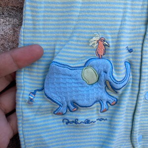 Puede incluir: Mono de beb&eacute; a rayas azules y amarillas con un dise&ntilde;o bordado de elefante y p&aacute;jaro. El mono tiene el texto "Baby" bordado en la parte inferior.