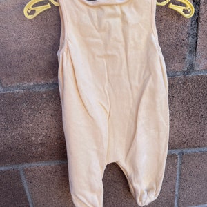 K&ouml;nnte beinhalten: Ein hellgelber, &auml;rmelloser Baby-Strampler mit dem Aufdruck "Carter's" auf der Vorderseite.