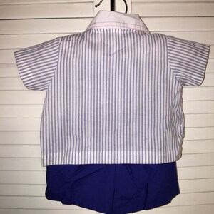May include: A white and blue striped short-sleeved shirt with a white collar and a blue pair of shorts.