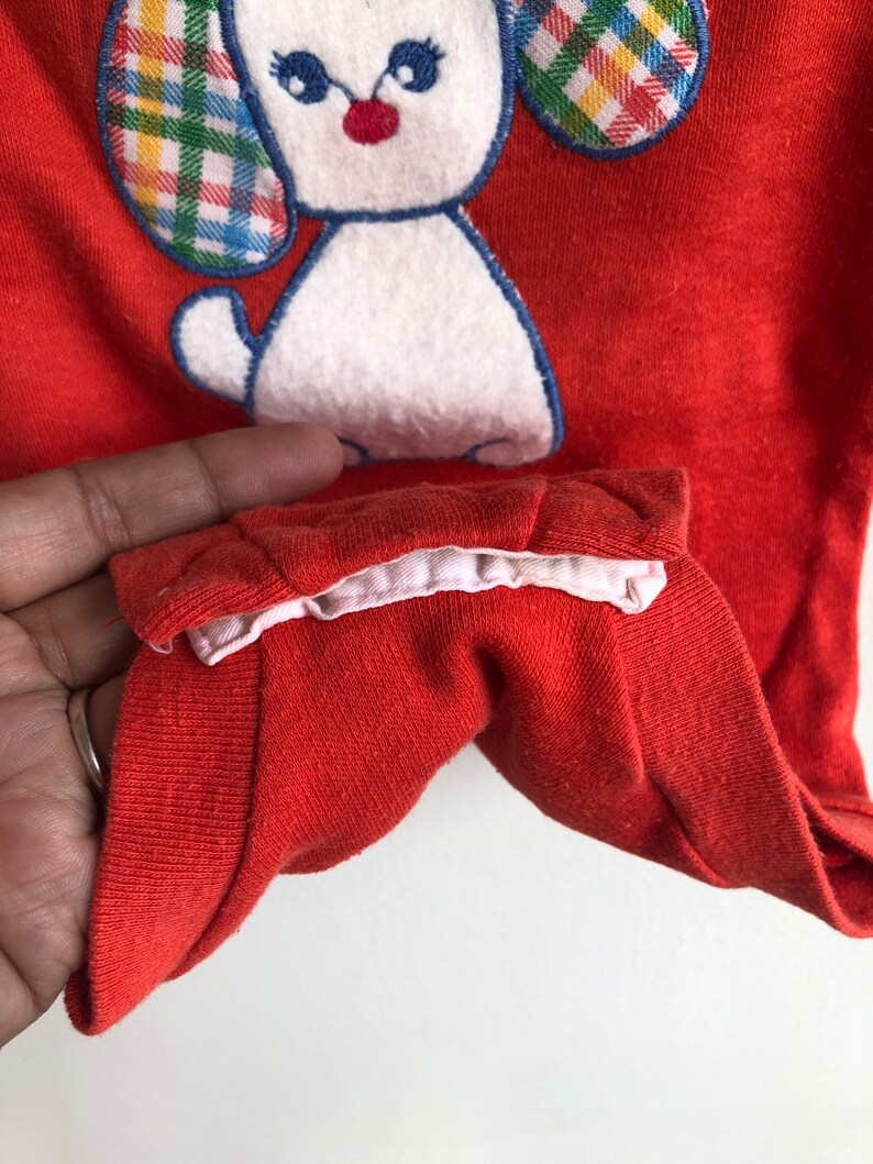 Puede incluir: Mono de beb&eacute; rojo con un cachorro blanco bordado con orejas a cuadros. El mono tiene un ribete blanco alrededor del cuello.