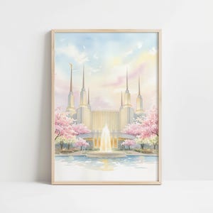 Puede incluir: Pintura a la acuarela de un templo con múltiples agujas, rodeado de cerezos en flor rosas y una piscina reflectante. El cielo pasa del azul al rosa y al amarillo. La obra de arte está enmarcada en un marco de madera clara.