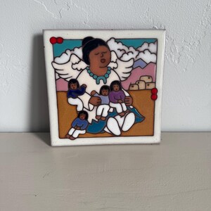 Könnte beinhalten: Eine Keramikfliese mit einer farbenfrohen Illustration einer Frau mit Flügeln, die vier Kinder hält. Die Frau trägt ein weißes Kleid mit einer türkisfarbenen Halskette und einem blauen Rock. Die Kinder tragen bunte Kleidung. Der Hintergrund ist hellbraun mit blauem Himmel und weißen Wolken.