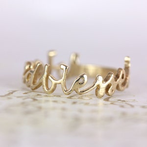 May include: A gold ring with the word "forever" written in cursive script.