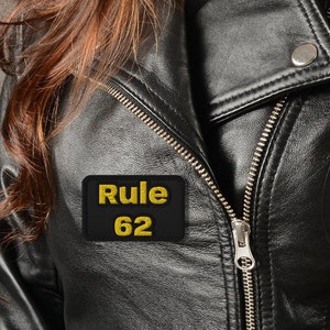 May include: A black leather jacket with a gold patch that says "Rule 62" on it.