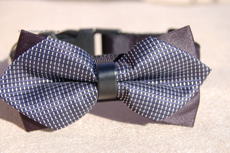 May include: A black and white patterned bow tie with a black leather strap. The bow tie is attached to a black collar.