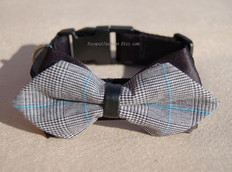 May include: A black dog collar with a gray and blue plaid bow tie. The collar has a black buckle and the text "Yoyopetfashion.Etsy.com" is printed on the collar.