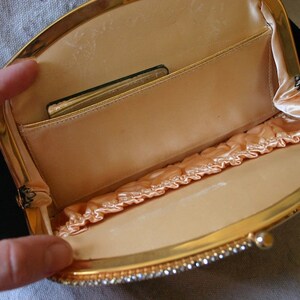 Peut inclure: Un sac de soir&eacute;e en velours noir avec une monture en m&eacute;tal dor&eacute; et une doublure en satin. Le sac a une fermeture &agrave; fermoir et une petite poche &agrave; l'int&eacute;rieur.
