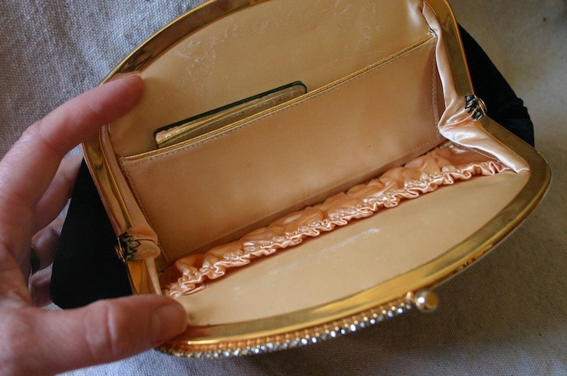 Peut inclure: Un sac de soir&eacute;e en velours noir avec une monture en m&eacute;tal dor&eacute; et une doublure en satin. Le sac a une fermeture &agrave; fermoir et une petite poche &agrave; l'int&eacute;rieur.