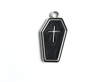 May include: A silver-colored metal charm shaped like a black coffin with a white cross on the front.
