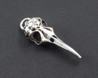 May include: Silver bird skull charm with a flower detail. The charm has a loop for attaching to a necklace or bracelet.