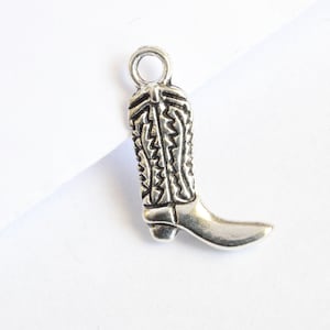 May include: Silver charm in the shape of a cowboy boot with a detailed design.
