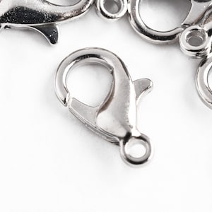 May include: Silver-toned metal lobster claw clasps, a type of fastener used in jewelry making.