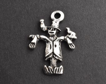 May include: A silver-colored charm in the shape of a scarecrow. The charm has a loop at the top for attaching to a necklace or bracelet. The scarecrow has a hat, a smiling face, and outstretched arms.
