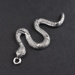 May include: A silver snake charm with a detailed, textured design. The snake is coiled and has a ring at the end of its tail.