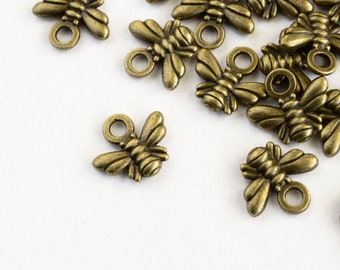 May include: A group of antique gold bee charms with a loop for attaching to jewelry or other crafts.